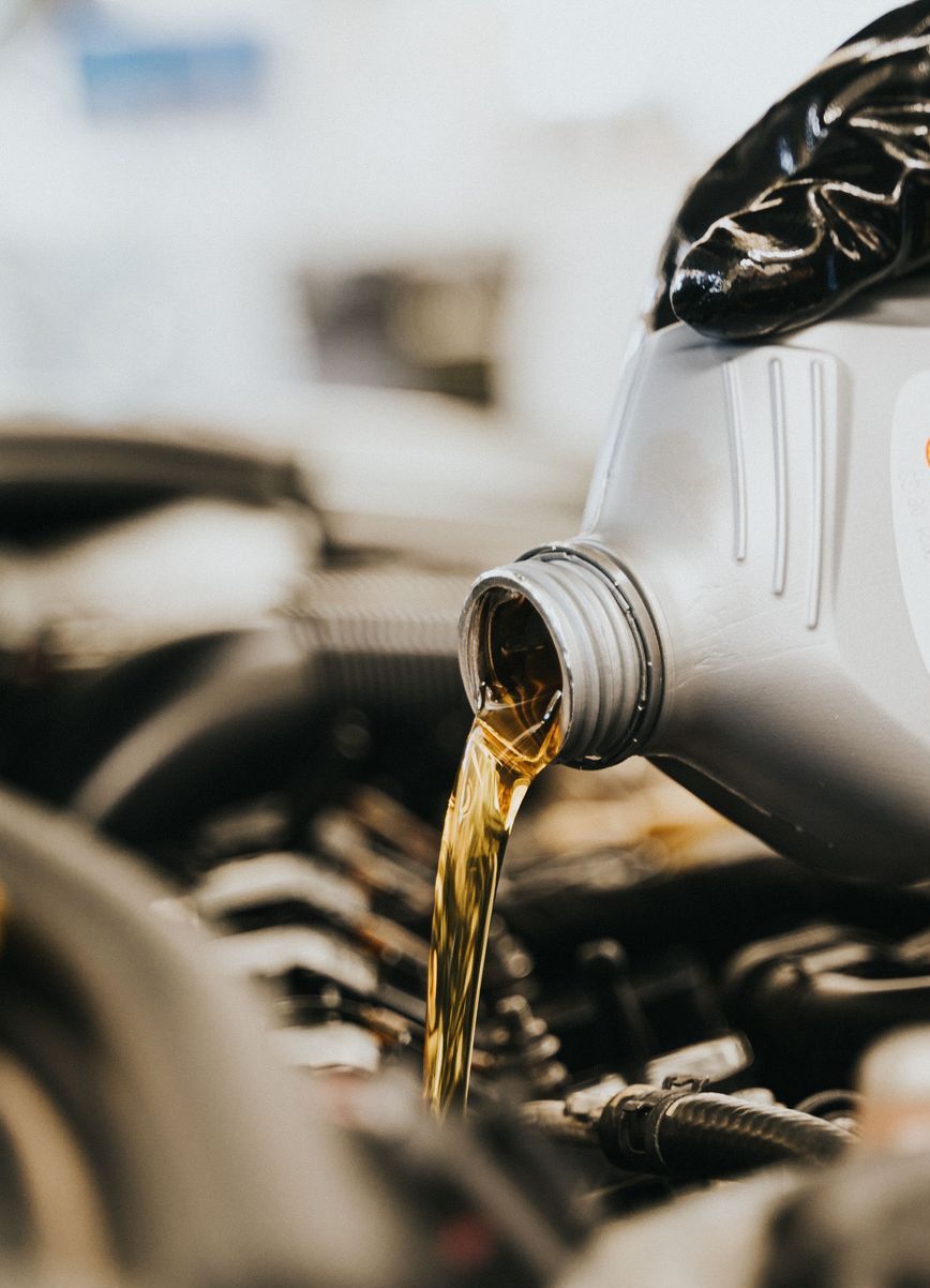 Close-up of a mechanic pouring engine oil into a car engine, highlighting maintenance work.